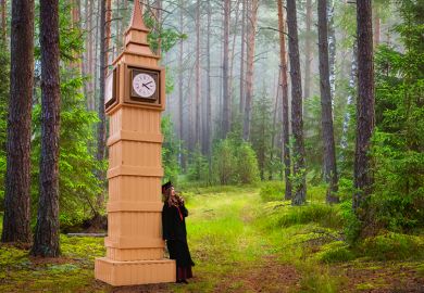 Graduate leaning on model of Big Ben in forest Graduate leaning on model of Big Ben in forest
