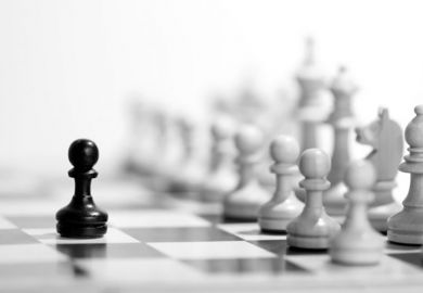 Black chess pawn in front of full set of white pieces