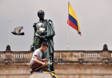A colombian youngster places the national flag and a bunch of white flowers at the bottom of Simon Bolivar's monument in Bogota.