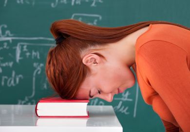 A bored academic leans her head on a book