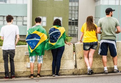 Brazilians with flags looking over wall