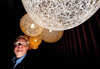 Nobel laureate Brian Schmidt looking up at lit up spheres Nobel laureate Brian Schmidt looking up at lit up spheres