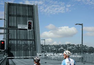 Two cyclists waiting at bridge  Two cyclists waiting at bridge