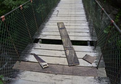 A wooden bridge with missing planks, symbolising precarity