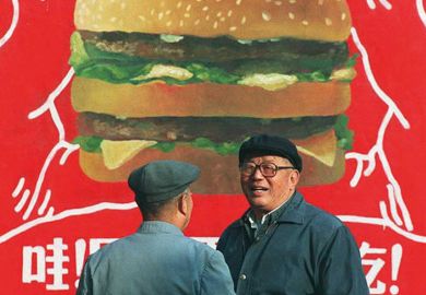Two Chinese men in front of a billboard advertisement for a burger