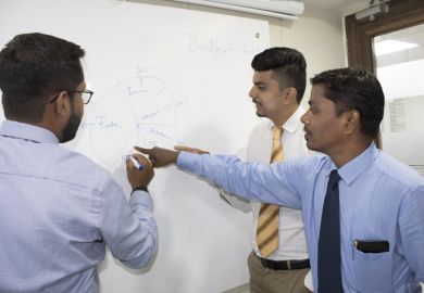 Indian business academics discuss a theory on a whiteboard Indian business academics discuss a theory on a whiteboard