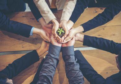 Business people hold a small plant, symbolising business school impact Business people hold a small plant, symbolising business school impact