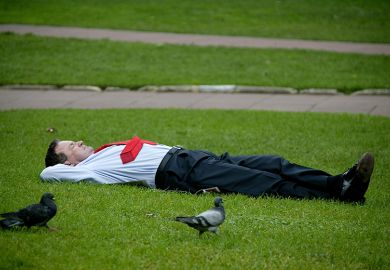 Sleeping businessman in a park on his lunch break, illustrating that employers are taking a back seat with regard to funding higher education. 