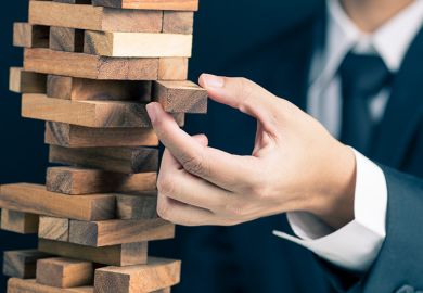 Businessman carefully removing wooden block from tower