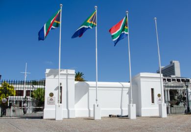 A homeless person sleeping under the South Africa flag at the Cape Town Parliament