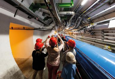 People in hard hats in tunnel at CERN lab People in hard hats in tunnel at CERN lab