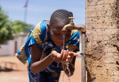 children drinking and playing with water in Bamako, Mali