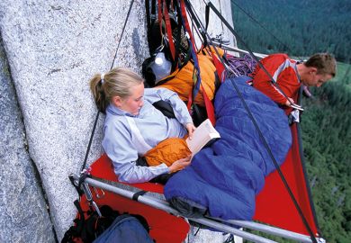Woman and man hanging on cliff