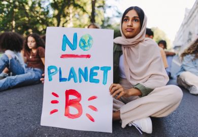 A climate protester sits in the road with "no planet B" sign A climate protester sits in the road with "no planet B" sign