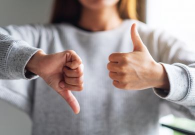 Closeup image of a woman making thumbs up and thumbs down hands sign