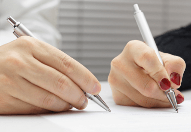 Two hands holding pens, illustrating co-authorship