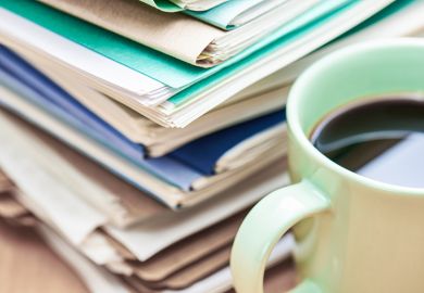 A stack of papers to mark and a cup of coffee
