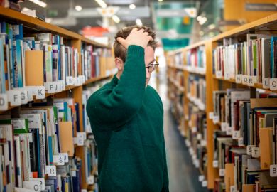 A man looks confused in a library aisle