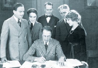 Filmmaker D. W. Griffith reviews the contract of Mary Pickford, accompanied by (l-r) her husband, Douglas Fairbanks, and Charlie Chaplin, and their two attorneys. Illustrating jump in teaching contracts under REF