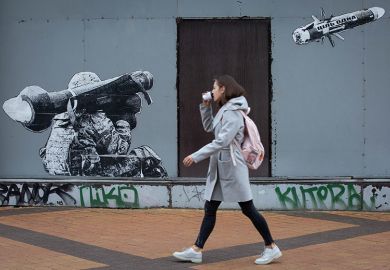 A woman passes by graffiti depicting a Ukrainian serviceman making a shot with a US-made Javelin portable anti-tank missile system in central Kyiv
