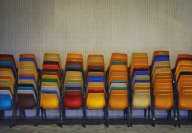 Colourful set of chairs piled up by a wall Colourful set of chairs piled up by a wall