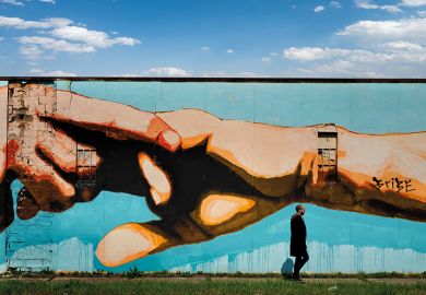 Man walking past mural of clasped hands