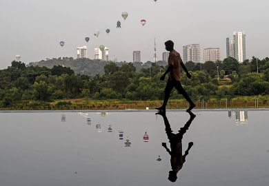 Cover of 24 June 2021 issue of Times Higher Education magazine Man reflected in water in Asian city on the cover of 24 June 2021 issue of Times Higher Education magazine