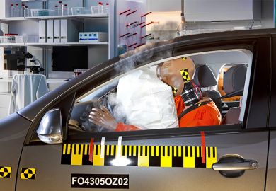 Crash test dummy in car crash with laboratory in the background. To illustrate how mid-career academic scientists can often get knocked back when applying for jobs.