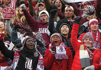 Crowd of Harvard University students cheering American football game