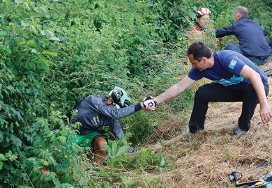 Two men helping cyclists who fell off their bikes