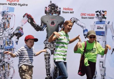 Children posing in front of picture of robots Children posing in front of picture of robots