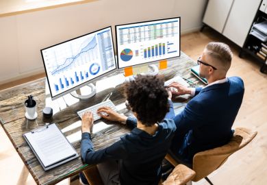 A black woman and a white man examine data charts