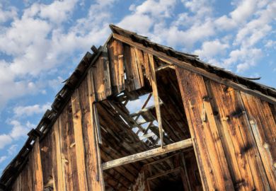 Derelict barn against cloudy blue sky