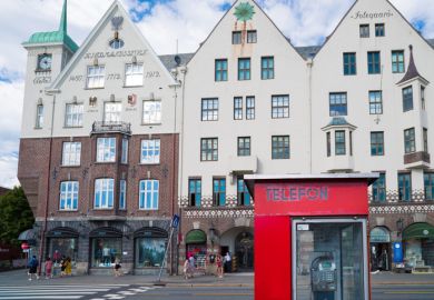 Detail of a red phone booth on the Bryggen promenade, the touristic hotspot of Bergen