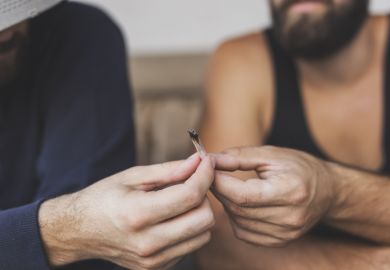 Detail of two men sitting on a couch, sharing a joint, smoking pot