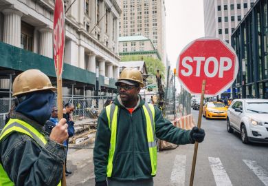 A minority ethnic man with a sign to stop traffic