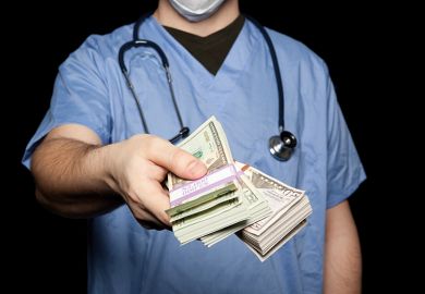 Male doctor holding out bank notes Male doctor holding out bank notes