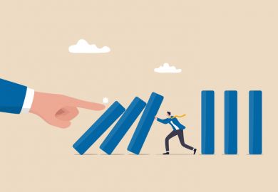 Illustration: a businessman tries to stop a line of falling dominoes, being pushed over by a giant hand