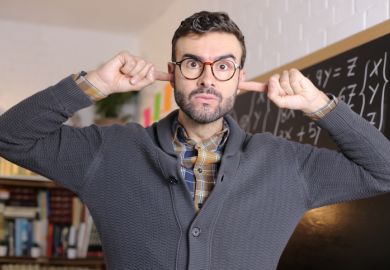 A lecturer puts his fingers in his ears, illustrating a resual to reflect