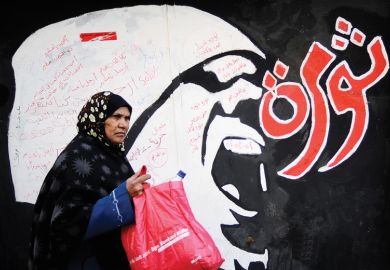Egyptian woman walks past 'Revolution' graffiti, American University in Cairo