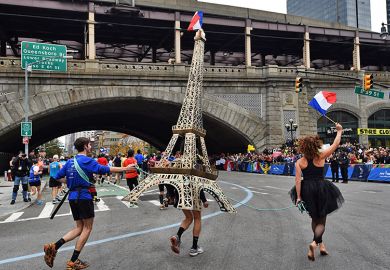 A runner carries a model of the Eiffel Tower during the New York City Marathon in New York, USA. To illustrate that European governments and institutions are launching schemes to attract US talent.