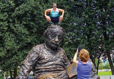 Man squatting on Albert Einstein memorial statue