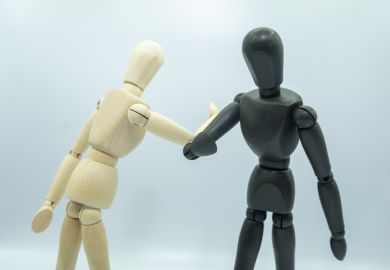A black and a white wooden mannequin elbow bump A black and a white wooden mannequin elbow bump illustrating EDI, equality diversity inclusion policy