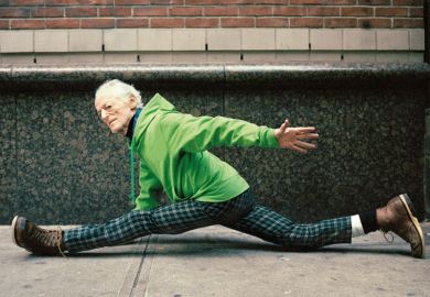 Elderly man doing spilts on street pavement
