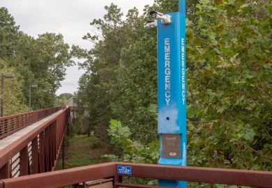 Emergency blue light pole in quiet wooden foot path area