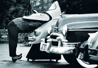 man looks under car bonnet