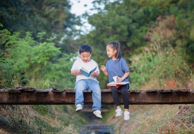 Two children read books on a bridge, symbolising humanities students becoming engineers