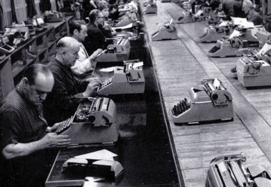 Men typing in a row in a factory Men typing in a row in a factory
