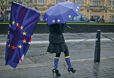 Person holds Union Jack and European Union flag and umbrella