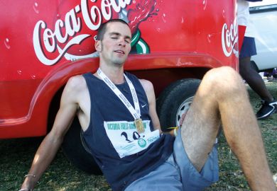 Exhausted marathon runner sitting by Coca-Cola branded vehicle